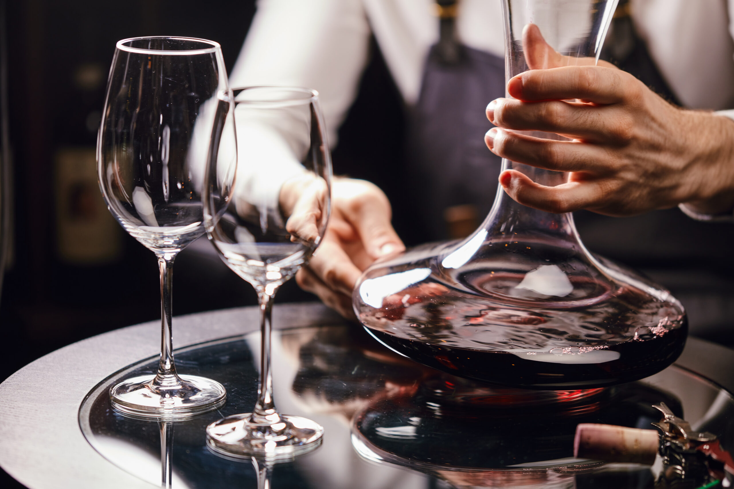 A sommelier decanting red wine into a glass